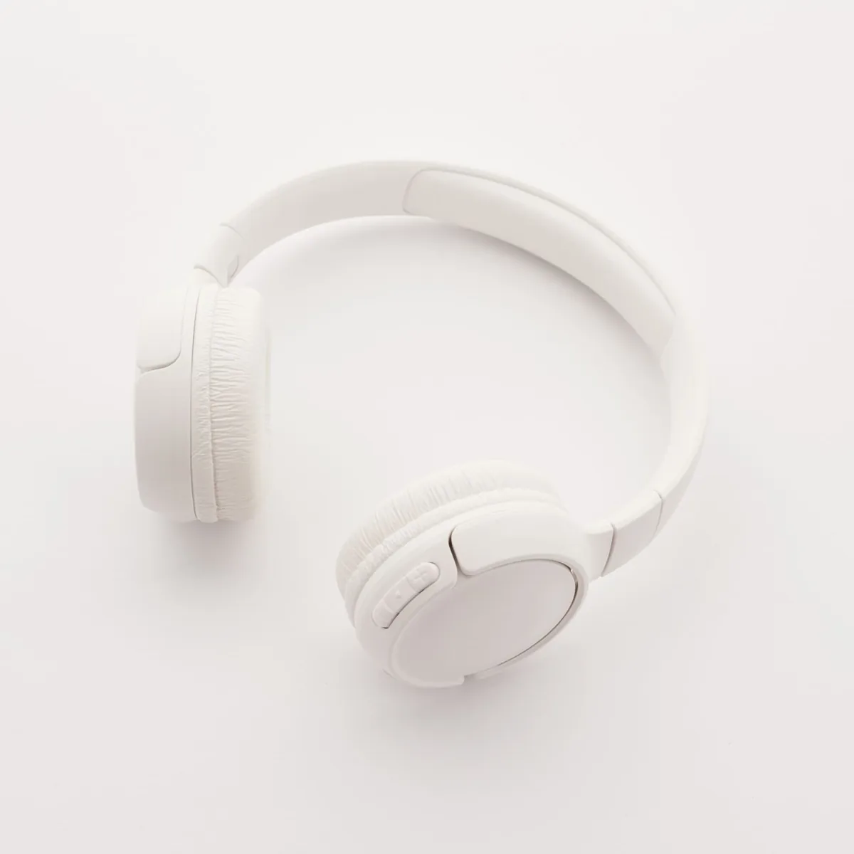 Auriculares blancos de diadema sobre un fondo claro